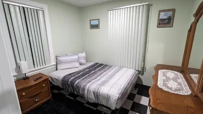 a bedroom with a bed and a dresser and two windows at Adirondack Spirit in Gloversville