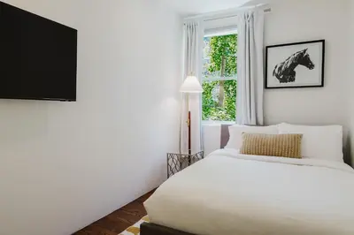 a bedroom with a white bed and a window at Designer Home in Diplomat District in New York