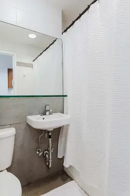 a bathroom with a sink and a toilet and a mirror at Designer Home in Diplomat District in New York