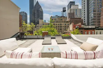 a rooftop patio with white furniture and a city skyline at Designer Home in Diplomat District in New York