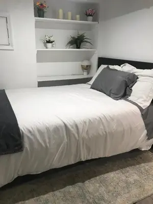 a bed with white sheets and pillows in a bedroom at 25-30 mins to Times Sq! in Corona
