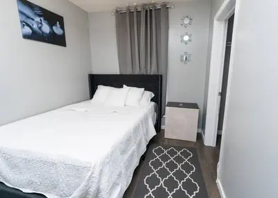 a bedroom with a bed with white sheets and a rug at Elegant Apt by EWR & PennStation in Newark