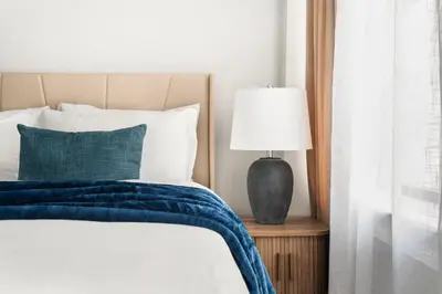 a bed with a blue blanket and a lamp on a table at 73-703 New Studio UWS Doorman Gym in New York