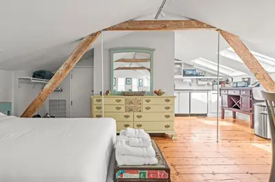 a bedroom with a white bed and a yellow dresser at Studio Flat Above Historic Cider Mill in Westport