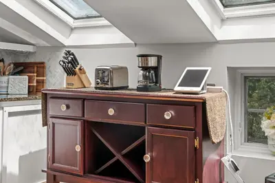 a kitchen with a wooden cabinet with a coffee maker on it at Studio Flat Above Historic Cider Mill in Westport