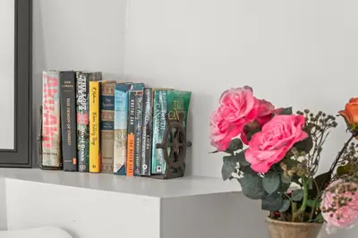 a row of books on a shelf with a vase of roses at Studio Flat Above Historic Cider Mill in Westport