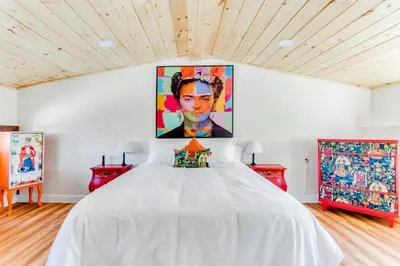 a bedroom with a white bed with a large painting on the wall at 2BR Flat above Historic Cider Mill in Westport