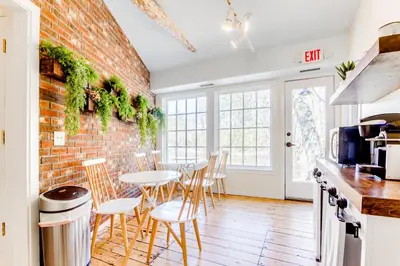a kitchen with a brick wall and tables and chairs at 2BR Flat above Historic Cider Mill in Westport