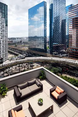 a rooftop patio with couches and a view of a city at Hilton Garden Inn Long Island City in Queens