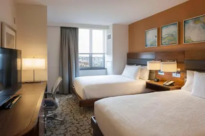 a hotel room with two beds and a flat screen tv at Hilton Garden Inn Long Island City in Queens
