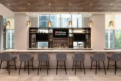 a bar in a hotel with chairs around it at Hilton Garden Inn Long Island City in Queens