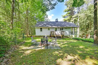 a white house in the middle of a yard at Becket Home with 3-Season Porch Walk to Lake Access in Becket
