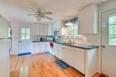a kitchen with white cabinets and a ceiling fan at Becket Home with 3-Season Porch Walk to Lake Access in Becket