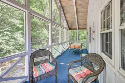a screened in porch with wicker chairs and windows at Becket Home with 3-Season Porch Walk to Lake Access in Becket
