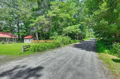 an empty dirt road with trees and a house at Becket Home with 3-Season Porch Walk to Lake Access in Becket
