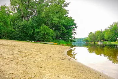 a sandy beach next to a body of water at Becket Home with 3-Season Porch Walk to Lake Access in Becket
