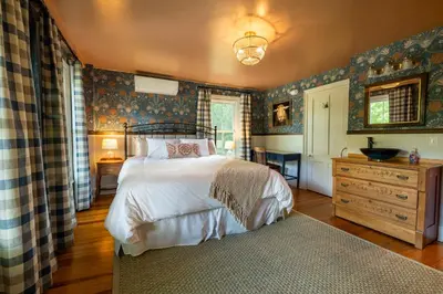 a bedroom with a bed and a dresser and a table at Wilder House Berkshires in Sheffield