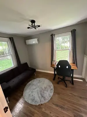 a living room with a couch and a table and two windows at 3BR, 2BA and Office Fire Pit,Mins 2 UConn & Lake in Coventry