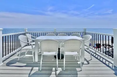 a white table and chairs on a balcony with the ocean at Charming 3 bedroom Beach Front Cottage in Milford