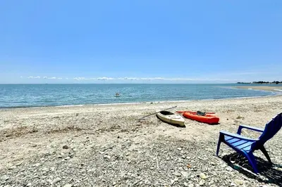 a blue chair and a boat on a beach at Charming 3 bedroom Beach Front Cottage in Milford