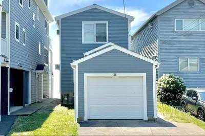 a blue house with a garage in front of it at Charming 3 bedroom Beach Front Cottage in Milford