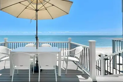 a table with chairs and an umbrella on the beach at Charming 3 bedroom Beach Front Cottage in Milford