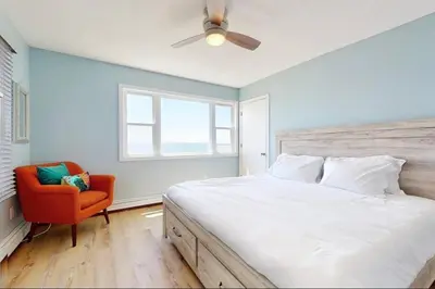 a bedroom with a bed and a red chair at Charming 3 bedroom Beach Front Cottage in Milford