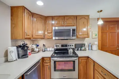 a kitchen with wooden cabinets and a stove and microwave at Walk to Memorial Park Pet-Friendly Bethlehem Home in Bethlehem