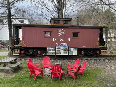 a group of red chairs and a table and a train car at Private Cottage with Hot Tub in the Woods in Thompson
