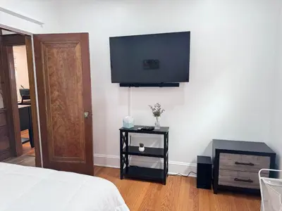 a bedroom with a bed and a tv on the wall at Modern and Cozy Pine Hills Home from Early 1900s in Albany