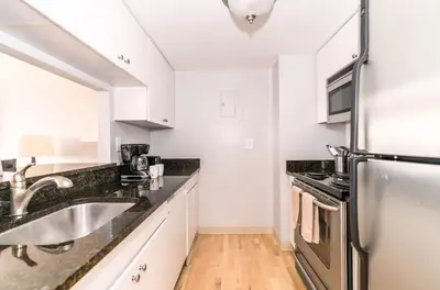 a kitchen with white cabinets and a stainless steel refrigerator at Spacious Apt Downtown in Stamford