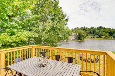 a wooden deck with a table and chairs and a lake at Lakefront Hinsdale Home about 10 Mi to Pittsfield! in Hinsdale