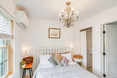 a bedroom with a white bed and a chandelier at Lakefront Hinsdale Home about 10 Mi to Pittsfield! in Hinsdale