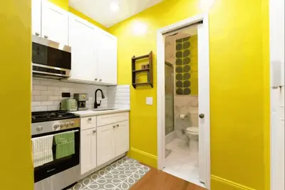a yellow kitchen with a sink and a toilet at The Green Room: 70s Groove Themed Studio in New York