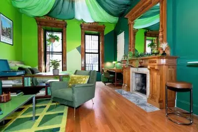 a living room with green walls and a fireplace at The Green Room: 70s Groove Themed Studio in New York