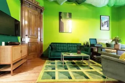a green living room with a couch and a table at The Green Room: 70s Groove Themed Studio in New York