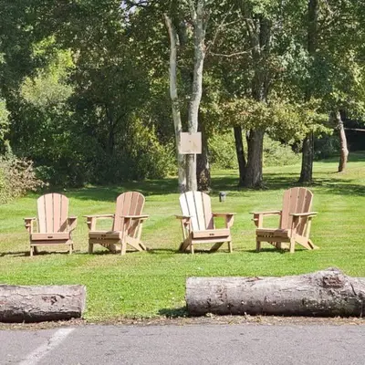 three chairs sitting in the grass next to a tree at Private Apartment in Southbury 102 in Southbury