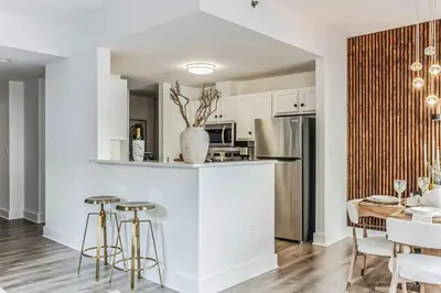 a kitchen with white cabinets and a table with stools at Luxurious 1BR Downtown Stamford in Stamford