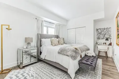 a white bedroom with a large bed and a chair at Luxurious 1BR Downtown Stamford in Stamford