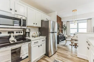 a kitchen with white cabinets and a stainless steel refrigerator at Luxurious 1BR Downtown Stamford in Stamford