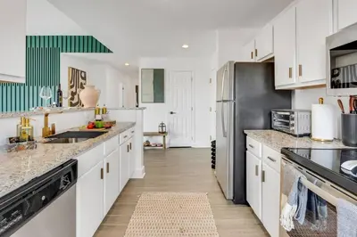 a kitchen with white cabinets and a stainless steel refrigerator at Penthouse Perfection with Unmatched Skyline Views in Stamford