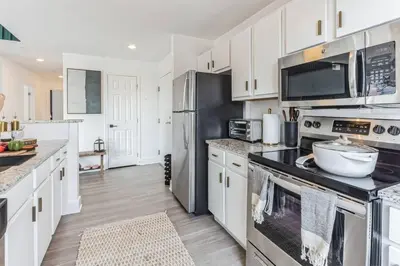 a kitchen with white cabinets and stainless steel appliances at Penthouse Perfection with Unmatched Skyline Views in Stamford