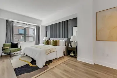 a white bedroom with a large bed and a chair at Penthouse Perfection with Unmatched Skyline Views in Stamford