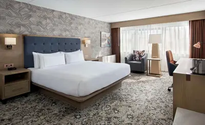 a hotel room with a large bed and a chair at DoubleTree by Hilton Poughkeepsie in Poughkeepsie