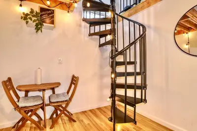 a spiral staircase in a living room with a table and chair at NYC Loft Studio Near MetLife World Cup Stadium & Times Square in North Bergen