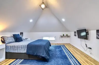 a attic bedroom with a bed and a tv at NYC Loft Studio Near MetLife World Cup Stadium & Times Square in North Bergen
