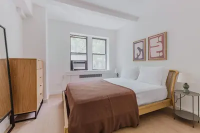 a white bedroom with a bed and a window at Blueground UES elev wd nr Museum Mile NYC-1530 in New York