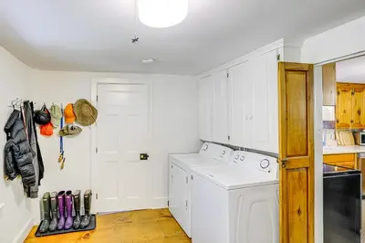 a kitchen with white cabinets and a washer and dryer at Historic Catskills Farmhouse Ski, Hike and Relax! in Catskill