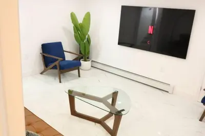 a living room with a glass table and a blue chair at Luxury king bed parking & washer in Schenectady