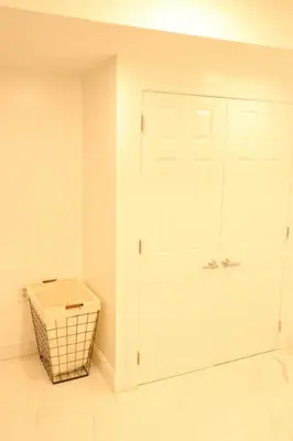a bathroom with a white door and a basket at Luxury king bed parking & washer in Schenectady
